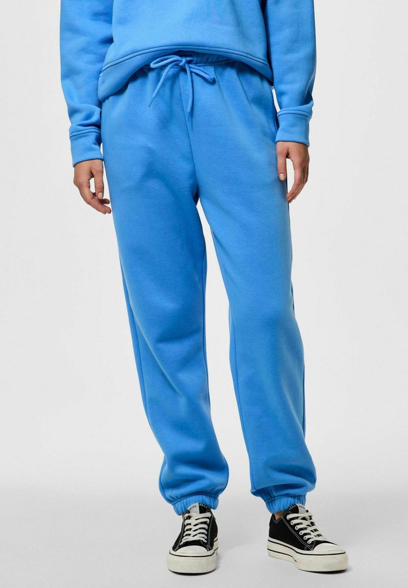 Pantalones de chándal azul cielo fabricados en tela suave, con cintura y puños elásticos, que cuentan con bolsillos laterales y un detalle de cordón.