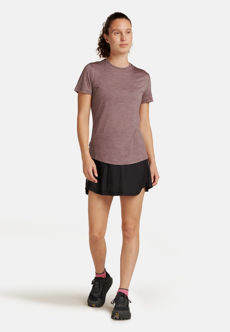 Leichtes, kurzärmliges Performance-T-Shirt in Weinrot, kombiniert mit einem schwarzen Sportrock. Dazu schwarze Schuhe und Socken mit pinken Akzenten.