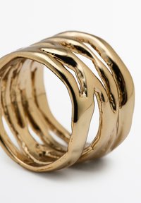 Gouden metalen ring met een golvend ontwerp, met meerdere onderling verbonden banden en een gepolijste, reflecterende oppervlakte.