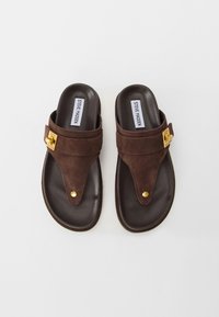 Brown suede Steve Madden sandals with toe post and gold metal buckle detail on a white background.