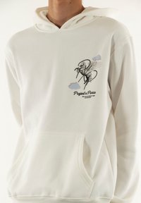 Hoodie blanc en tissu doux, doté d'une poche avant, d'une capuche avec cordon de serrage et d'un design imprimé avec un cheval ailé et du texte.