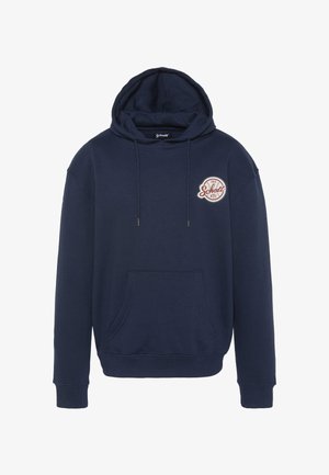 Marineblå hættetrøje lavet af blødt stof med en forlommer, snøre i hætten og et rundt broderet logo på brystet.