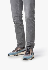 Färgglada sneakers med en blandning av blå, grå och bruna material. Designade med texturerade accenter och en tjock svart sula.