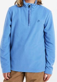 Jasnoniebieski polarowy pulower z półwysokim kołnierzem i zamkiem błyskawicznym, z pionowym tekstem z przodu i miękką teksturą. Długie rękawy z prostym detalem wykończenia.