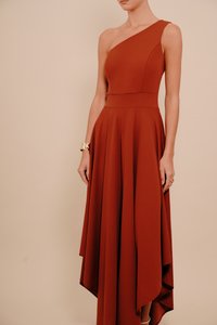 Rozsdaszínű, egyrészes ruha, melynek testhez simuló felsőrésze és réteges, leomló szoknyája van. Sima anyagból készült, magas-alacsony szegéllyel és elegáns szabással.