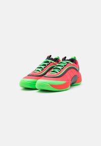 Sneakers med en levende rød og grøn farveskala, der har en tekstureret overdel, kontrasterende sorte detaljer og grønne snørebånd. Rundet således design.