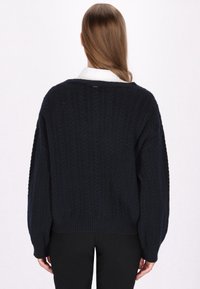 Marineblauw gebreid sweater met een gestructureerd kabelpatroon, losse pasvorm en ribbelzoom. Mouwen zijn verlaagd met brede manchetten. Achteraanzicht weergegeven.