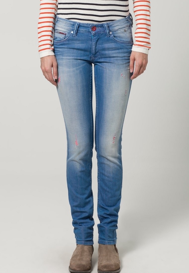 Ett par blekta blå skinny jeans med lätt slitage, femfickorsdesign och knappstängning. Bärs med beige ankelstövlar.