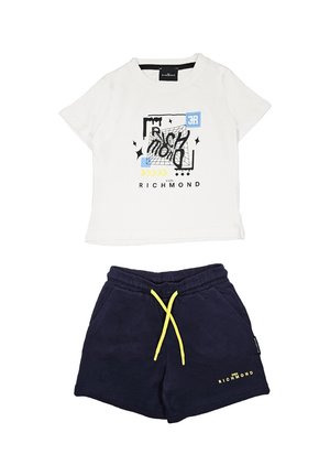 Maglietta in cotone bianca con stampa grafica e accenti neri, blu e gialli, abbinata a pantaloni corti blu navy con cordino giallo.