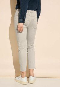 Ljusgrå beskurna byxor med en skräddarsydd passform, som har bakfickor och en slät tygtextur, matchat med vita sneakers.