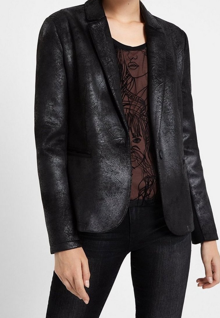 Blazer noir en simili cuir avec une texture lisse, fermeture à un bouton et revers crantés, porté sur un top à motifs.