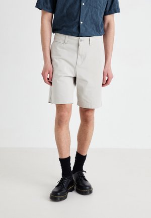 Light gray cotton shorts with a straight cut, featuring side pockets and a button closure, paired with black socks and shoes.