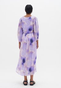 Long purple dress with puffy sleeves, featuring a watercolor pattern of dark blue and gold accents, and a cinched waist.