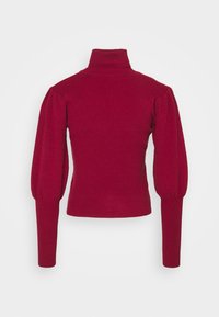 Pull en maille côtelée rouge avec un col montant, des manches longues bouffantes et des poignets ajustés, vu de dos sur fond uni.