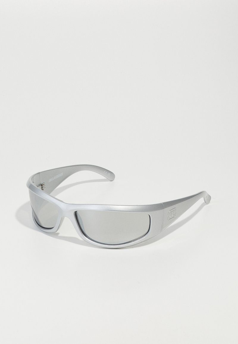Silberne Sportsonnenbrille mit schlankem Design, reflektierenden Gläsern und einem leichten Kunststoffrahmen. Auffälliges Logo an der Seite.