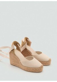 Sandales compensées en espadrille beige avec une plateforme en jute tressé, tige en tissu, bout rond et liens à la cheville pour un ajustement sécurisé.