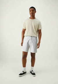 Beige cotton t-shirt, light gray shorts with a drawstring, black sneakers with white soles, and white crew socks. Simple design and fit.