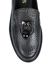 Czarne skórzane loafersy o fakturze, z srebrnym pierścieniem i czarnym kulistym ornamentem na górze, pokazane z góry na białym tle.