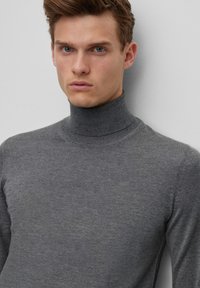 Szürke garbó pulóver, puha kötött anyagból készült. Fitting fazonú, magas gallérral rendelkezik, finom textúrával és látható minták nélkül.