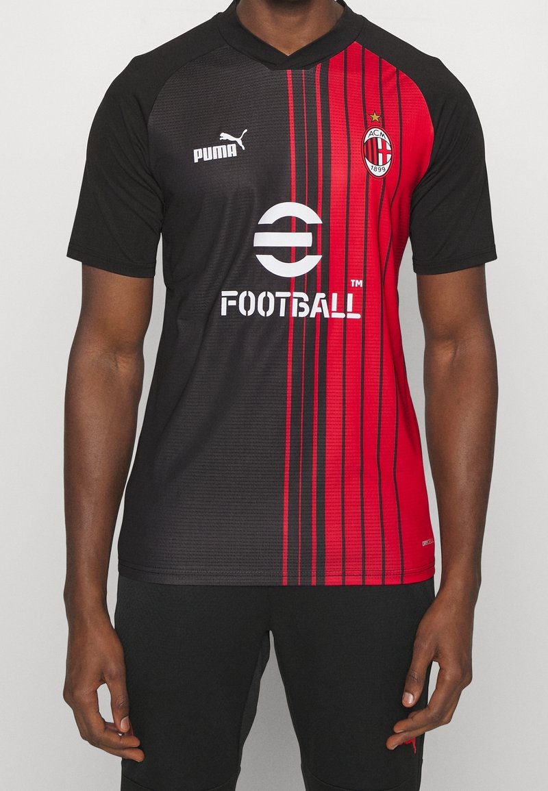 Camiseta de fútbol negra y roja con rayas verticales, mangas cortas y cuello en forma de V. Presenta logotipos en el pecho y una textura de patrón distintiva.