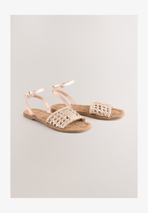 Ravne sandale s pletenim metalik gornjim dijelom u boji ružičastog zlata, mekanim antilop potplatom i podesivim remenčićima oko gležnja za sigurno pristajanje.