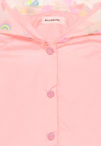 Ροζ αδιάβροχο με γυαλιστερή υφή, με κούμπωμα με κουμπιά και λεπτομέρειες με γκλίτερ, καθώς και κουκούλα με επένδυση σε πολύχρωμο μοτίβο με ουράνια τόξα και παγωτά.