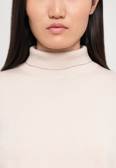 Light beige turtleneck sweater with a fine ribbed texture and fitted design, featuring a high collar and seamless construction.