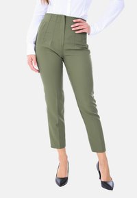 Pantaloni neri eleganti a vita alta in verde oliva, con pieghe, fitting slim, realizzati in tessuto liscio, abbinati a décolleté nere a punta.