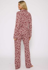 Lange mouw pyjama set in bordeaux met crèmekleurig luipaardprint. Zachte stof, relaxte pasvorm en bijpassende broek met rechte pijpen.