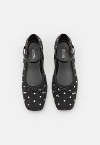 Black ballet flats made of fabric, featuring a bow detail, shiny rhinestones, and a slender ankle strap. Smooth, rounded toe design.