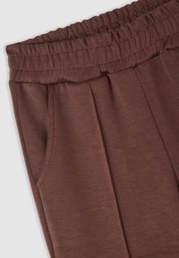 Pantaloni marroni con vita elasticizzata, davanti plissettato e tasche laterali. Tessuto liscio con una leggera lucentezza, progettati per comfort e facilità di indossatura.