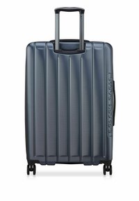 Donkergrijze harde koffer met verticale ribbels, uitschuifbare handgreep en vier wielen voor mobiliteit. Heeft merkaccenten.