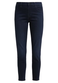 Jeans de denim azul oscuro con un corte ajustado, que cuentan con cinco bolsillos, un cierre de botón y costuras a tono. La tela tiene una textura suave.