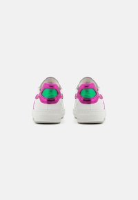Vita sneakers med rosa och gröna accenter, med en texturerad bakpanel och en gummisula. Designen inkluderar perforerade detaljer.