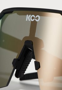 Black frame sunglasses with mirrored lenses, featuring a clip mechanism, angular design, and the logo "KCO" on the upper part of the lens.