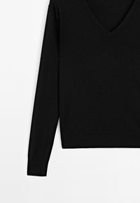 Maglione nero a V in morbido tessuto a maglia, con maniche lunghe e orlo dritto. Design semplice senza motivi o accenti visibili.