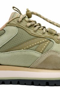 Zapatilla deportiva verde que combina materiales de malla y ante, con detalles texturizados y una suela acolchada con sistema de cordones.
