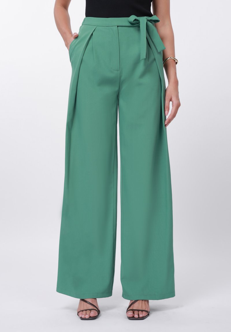 Zelene široke hlače iz gladkega blaga z zavezanim pasom, gubami spredaj in stranskimi žepi.