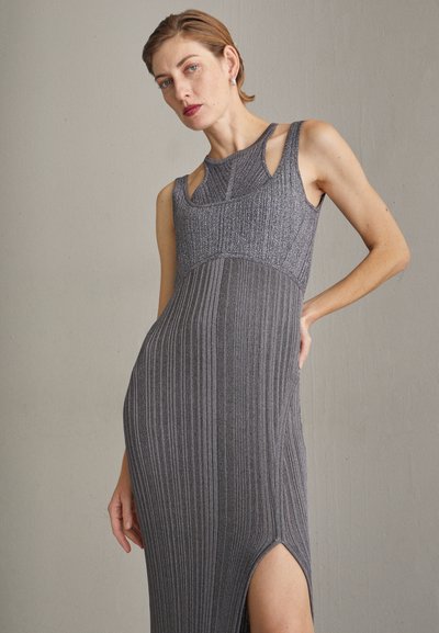Szürke bordás kötött ruha, ujjatlan dizájnnal, kivágott részlettel a nyaknál és combmagasságú hasítékkal az egyik oldalon.