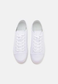 Adidași albi cu un superior textil neted, șireturi plate, tălpi din cauciuc și vârf rotunjit. Design simplu, curat, cu detalii minime.