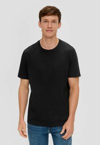 Schwarzes Baumwoll-T-Shirt mit kurzen Ärmeln und Rundhalsausschnitt. Kombiniert mit blauen Jeans, die eine glatte Textur und einen klassischen Schnitt bieten.