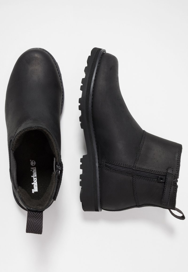 Paire de bottines en cuir noir avec fermeture éclair latérale et semelles robustes, l'une montrant une vue de dessus et l'autre une vue de côté.