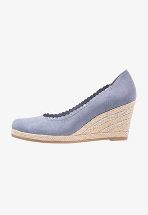Zapato con cuña en ante azul claro con detalle de borde ondulado. Cuenta con tacón envuelto en yute y punta cerrada. Suela plana de goma.