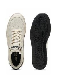 Cremefarvede sneakers med perforeret tå, flade snørebånd og sort gummisål. Har logo på siden og hælen samt detaljeret dækmønster.