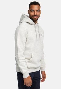 Felpa grigia chiara con cappuccio e cordino, tasca anteriore a soffietto e polsini a coste. Tessuto morbido e vestibilità rilassata, design casual.