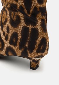 Bottines en imprimé léopard avec un talon moyen, en matériau textile lisse, et un mélange de motifs marron et noir.