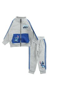 Survêtement gris en tissu doux avec des accents bleus. Veste zippée avec deux poches bleues et un personnage de dessin animé. Pantalon assorti avec des bandes latérales.