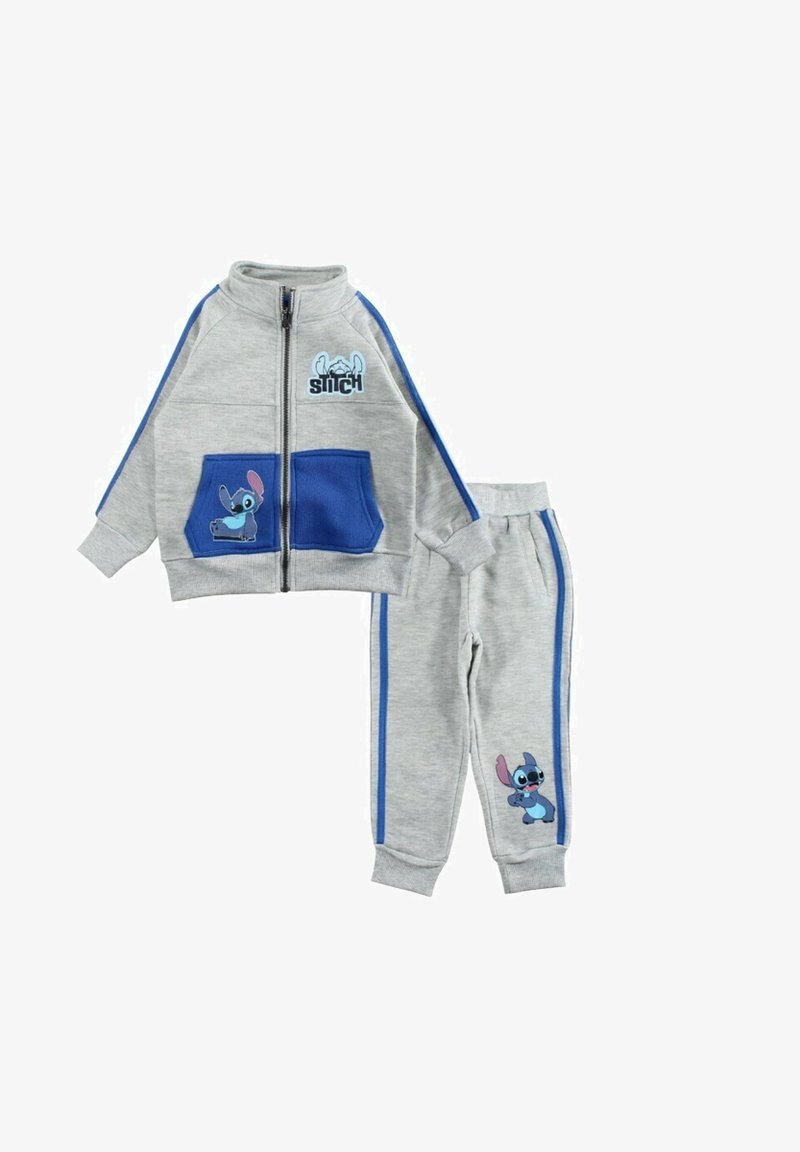 Survêtement gris en tissu doux avec des accents bleus. Veste zippée avec deux poches bleues et un personnage de dessin animé. Pantalon assorti avec des bandes latérales.