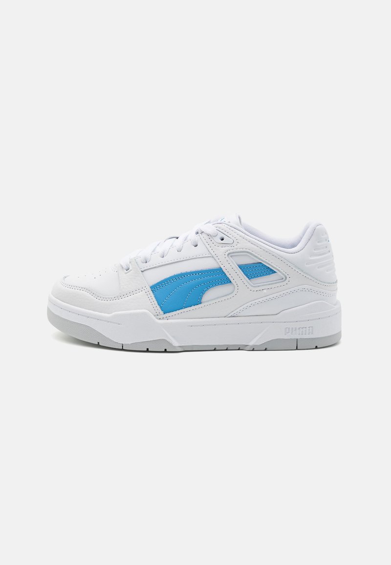 White sneakers with light blue accents, featuring a textured leather upper, flat laces, padded collar, and rubber sole with logo detail.