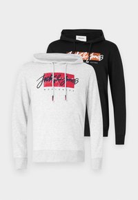 Dos sudaderas con capucha: una gris con un gráfico rojo y un texto negro, y una negra con un gráfico naranja, ambas con cordones ajustables.